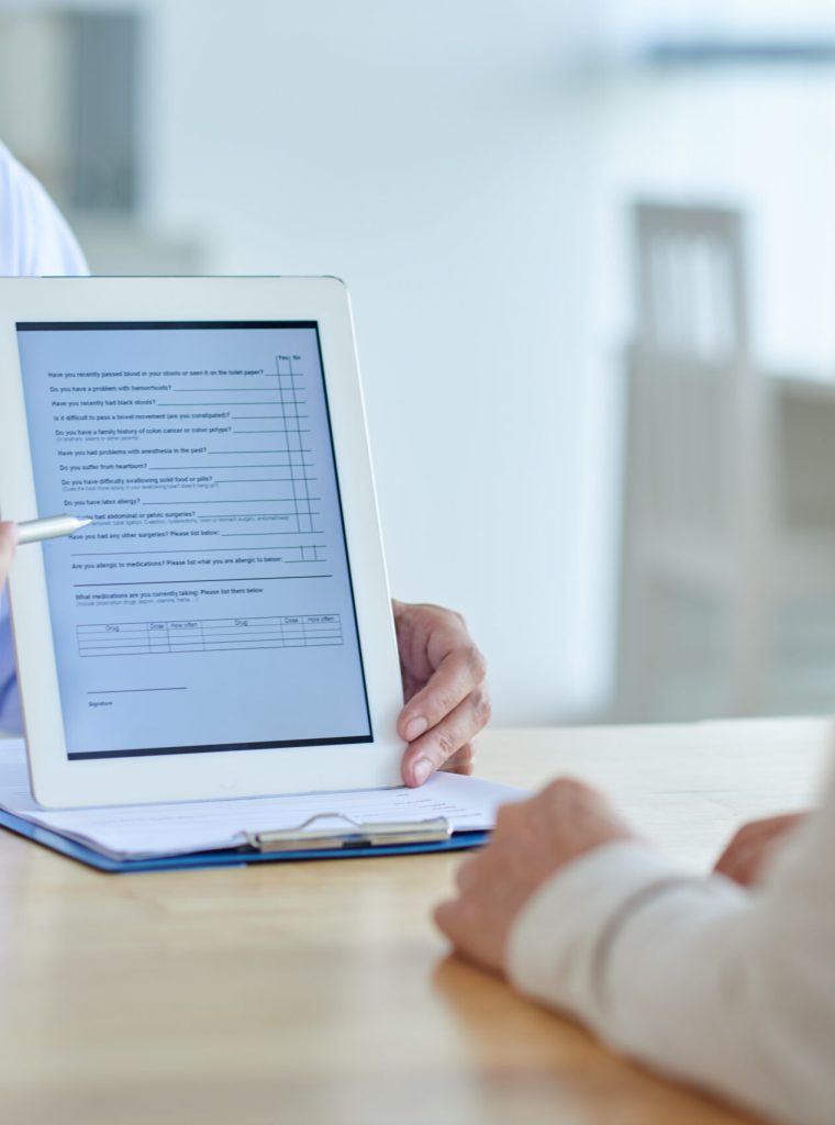 Close-up shot of physician pointing at screen of digital tablet, female patient listening to him with concentration